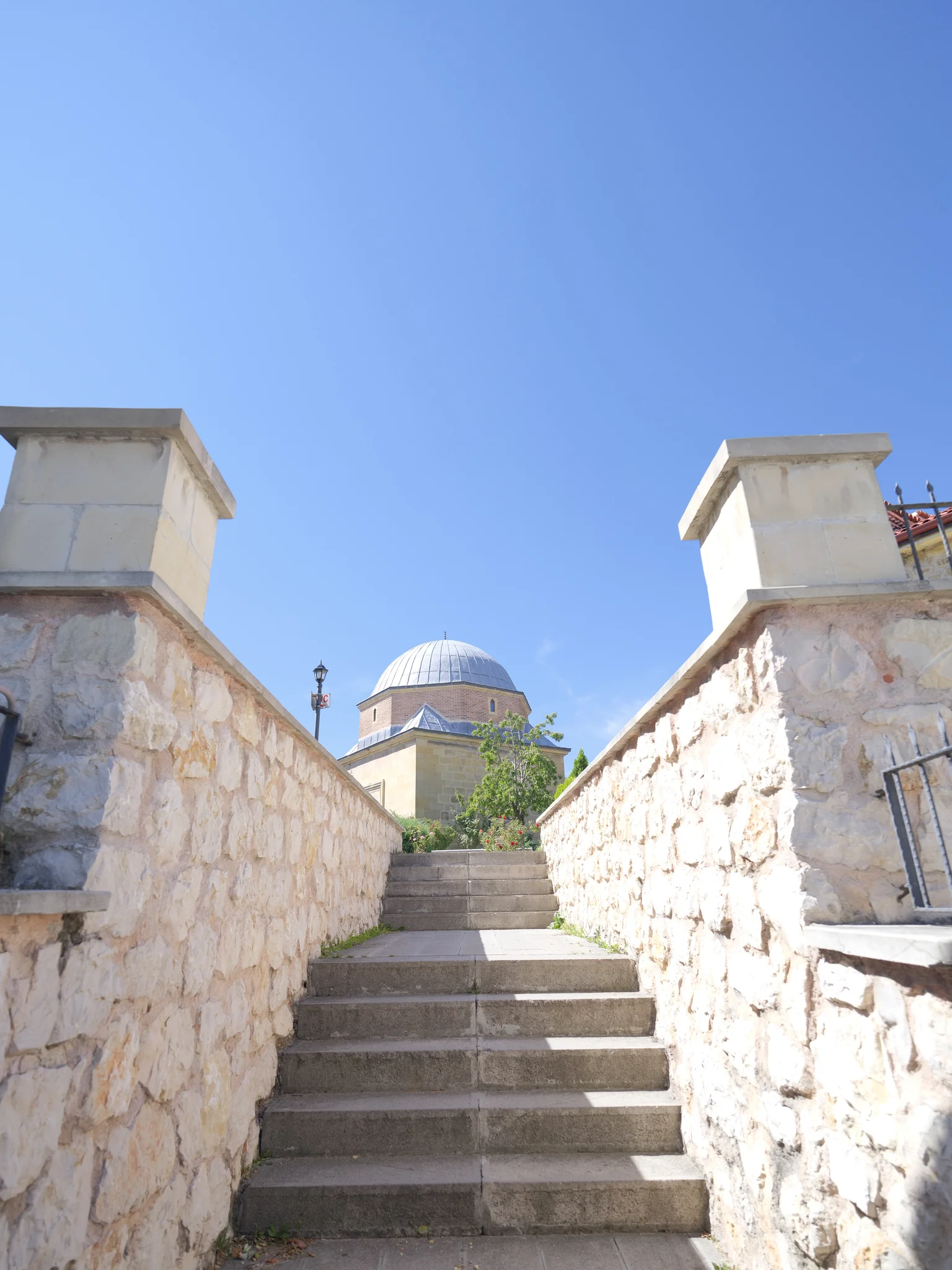 Stone steps leading up to the külliye; the mosque's dome in the background.